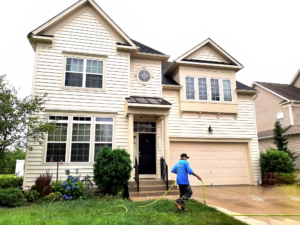 Freshly soft-washed house with a worker power washing the driveway, showcasing Blue Ridge Lawn Care's professional Power Washing and Soft Washing services in Northern Virginia.